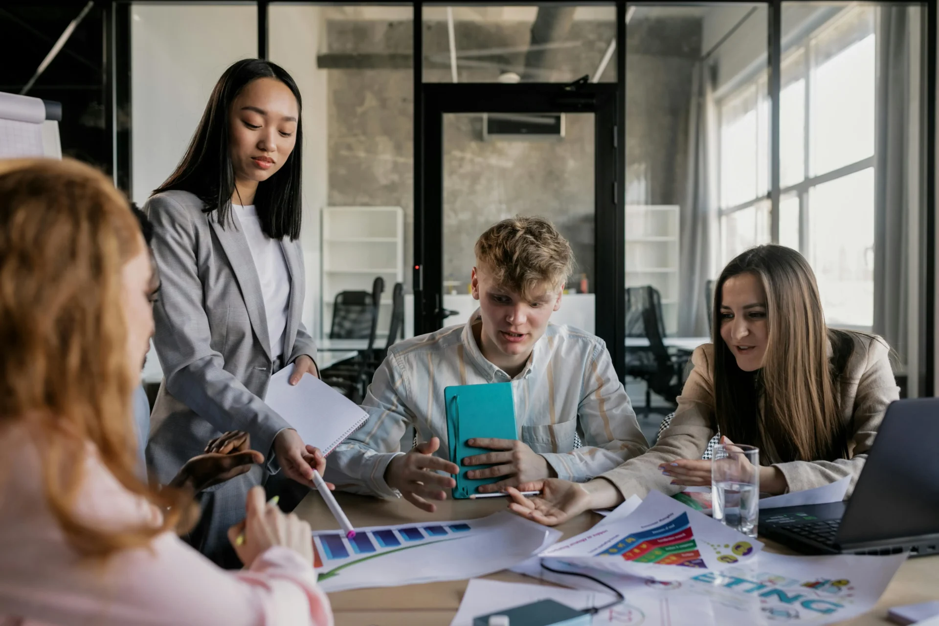 A diverse professional team in a modern office discussing data visualizations on a monitor to understand what is online marketing strategy performance.