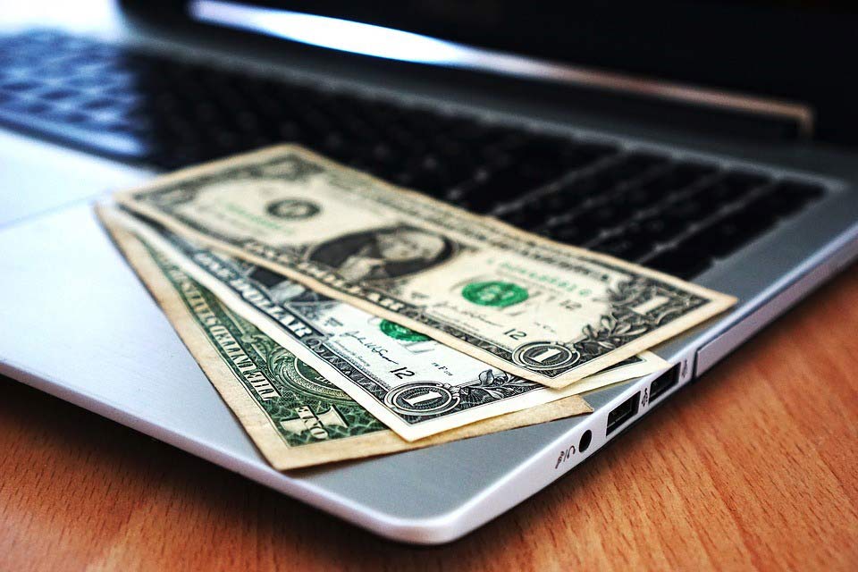 NYC web designer’s laptop with dollar bills on it
