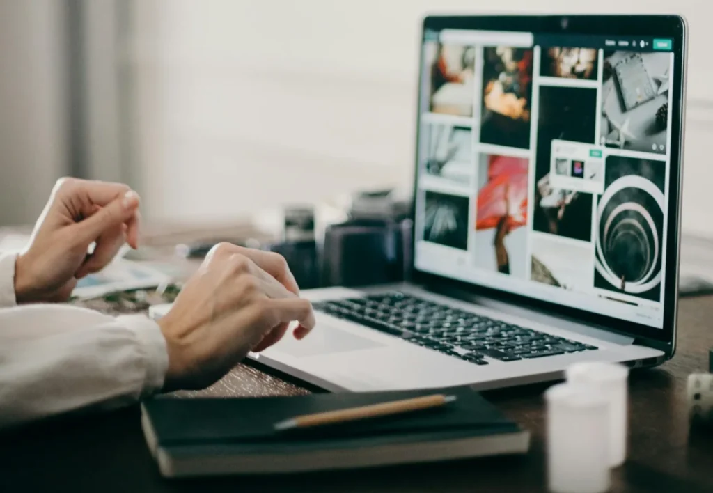 A designer sitting at a wooden desk using a laptop and sticky notes to plan UX web design basics.