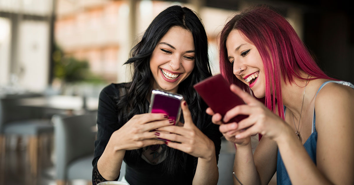 young smiling women looking at mobile phones