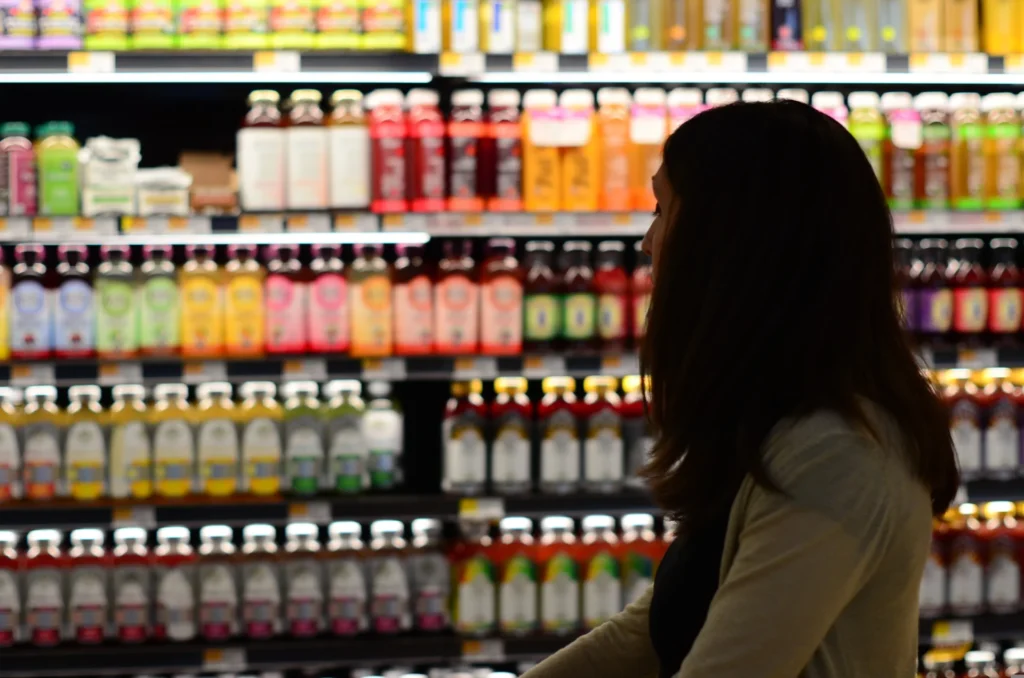 Customer shopping for beverages in a supermarket aisle, illustrating CPG marketing strategies