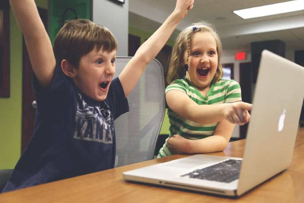 Two excited children engaging with interactive content on a laptop