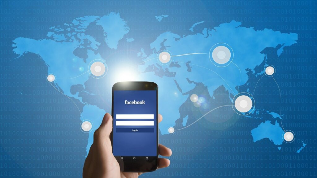 Hand holding smartphone with Facebook login screen, global map background, social media, digital marketing.