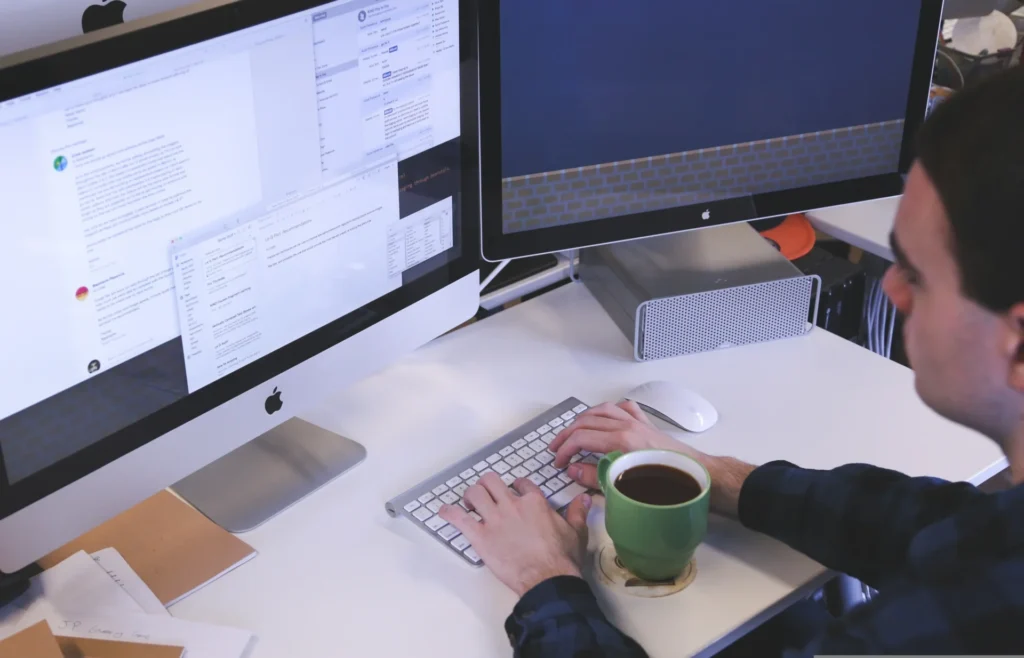 Man typing on a keyboard with multiple screens open, managing content strategy