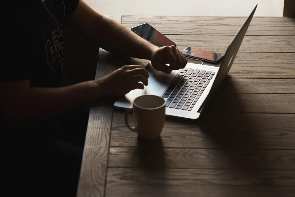 Person working on a laptop, with a phone and coffee nearby, likely planning a video marketing strategy.