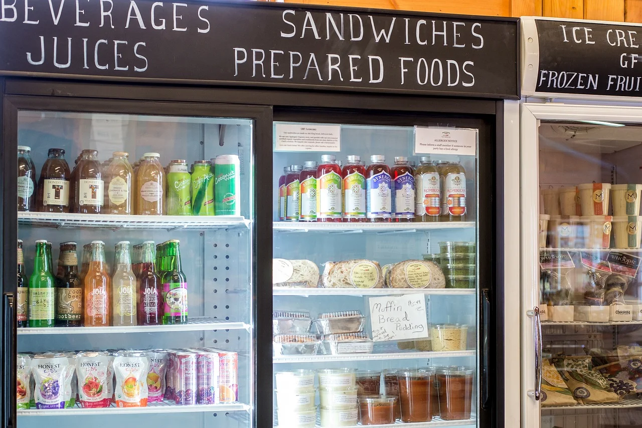 A refrigerated display case filled with various food and beverage products, including juices, sodas, and prepared foods.