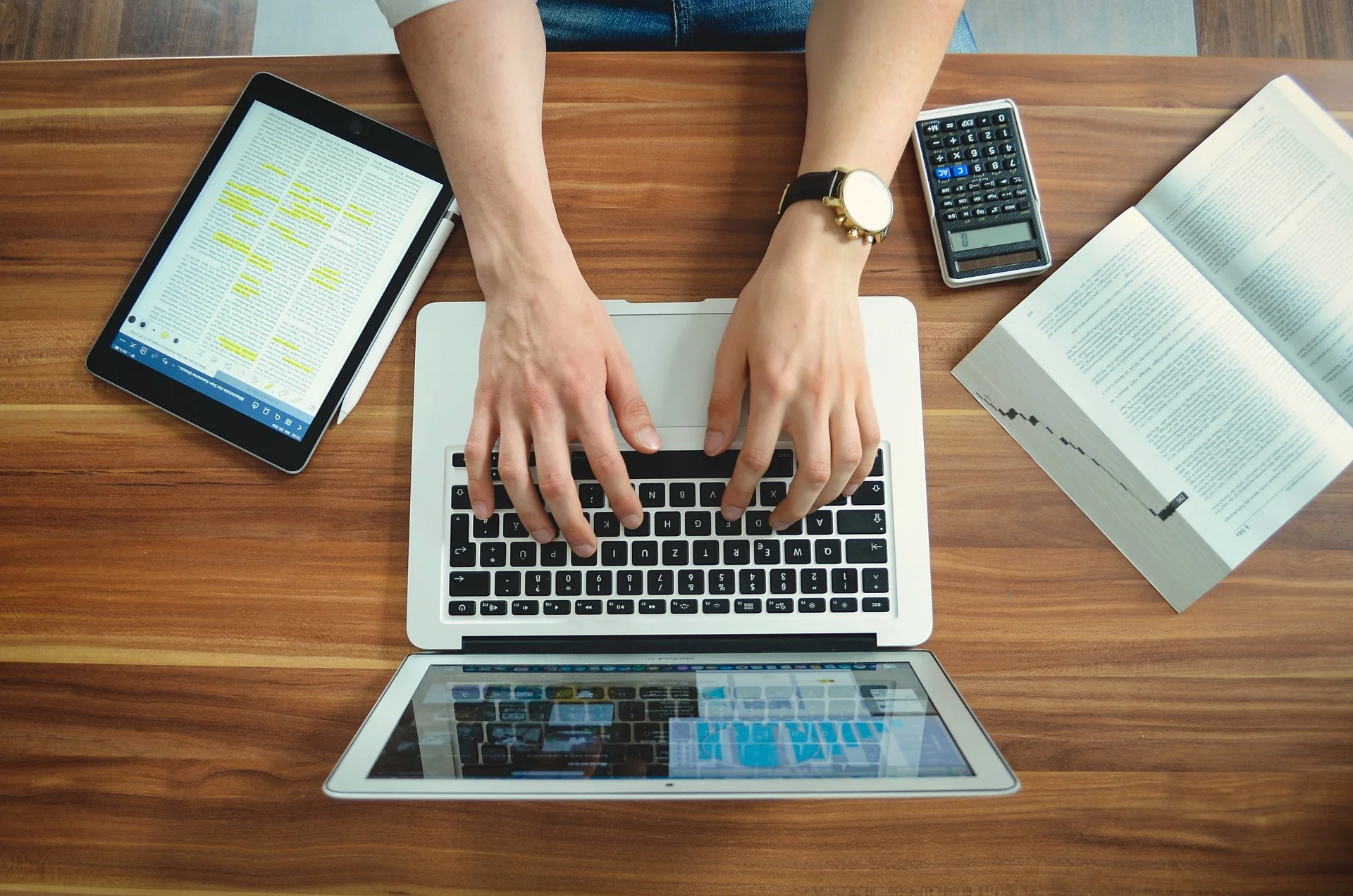 Digital marketing consultant working on a laptop, surrounded by documents and electronic devices.