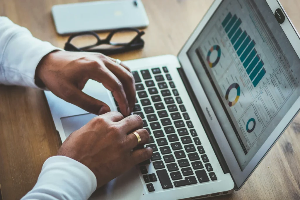 Close-up of hands typing on a laptop with CPG KPI charts on the screen