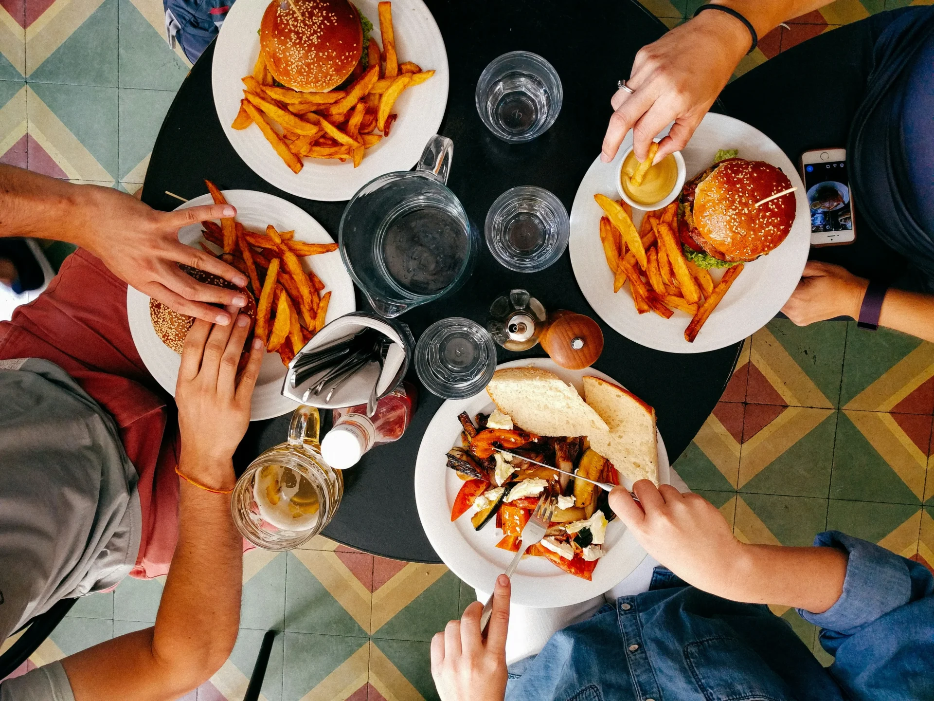 Flat lay photo of delicious food: burgers, fries, salad, and drinks, illustrating a visual marketing strategy for online food business.