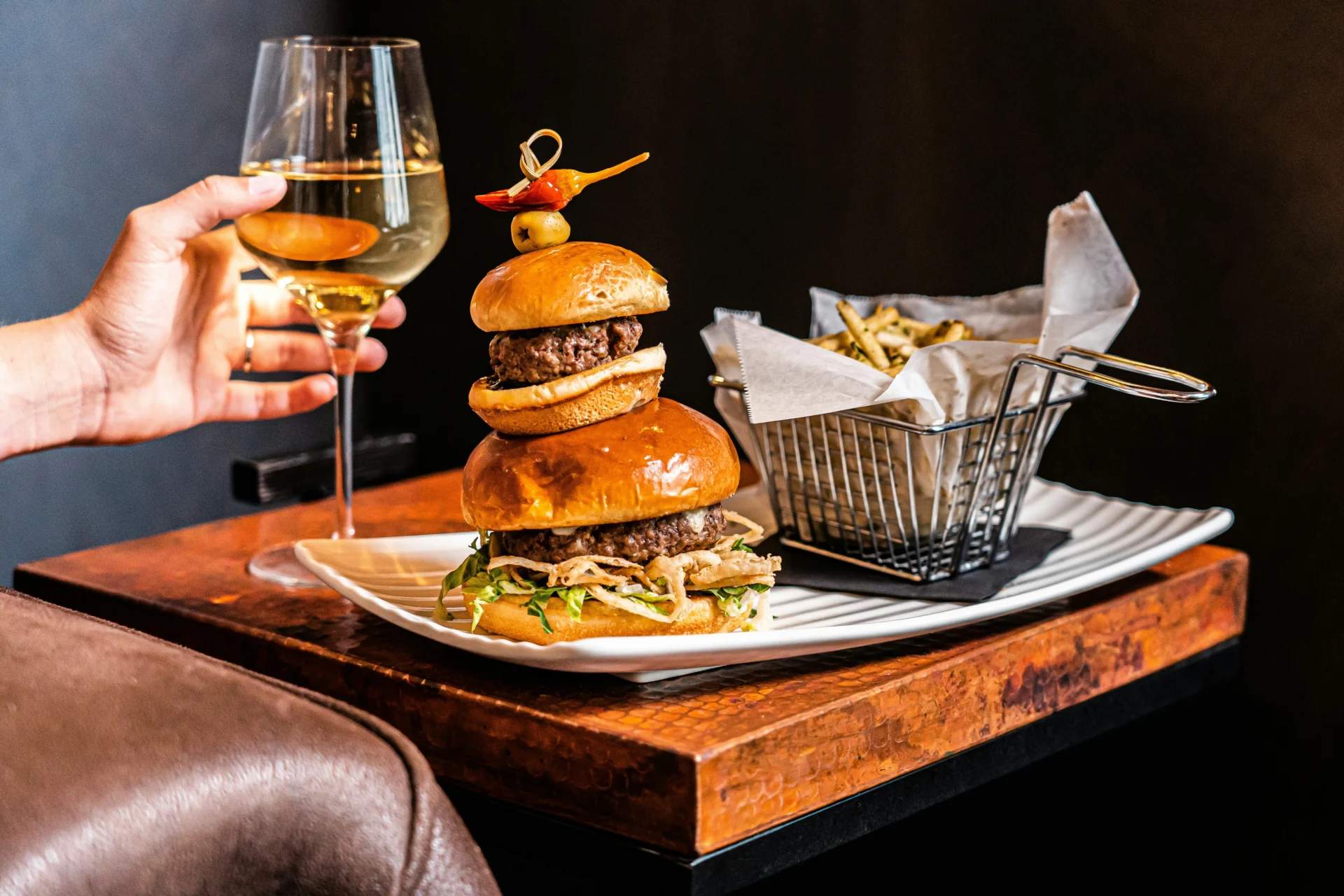 Stacked burger, fries, and wine, illustrating restaurant innovation for food and beverage strategy consulting.