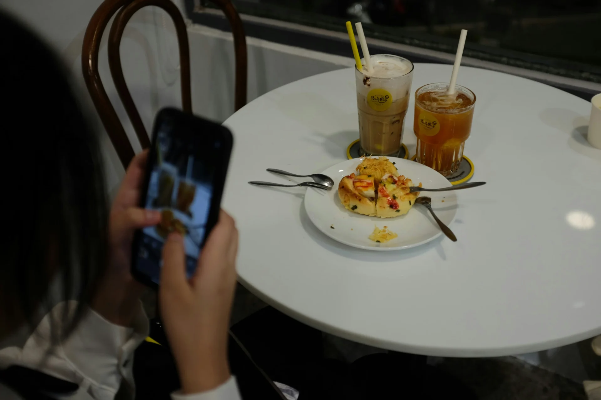 Close-up of hands using a smartphone to photograph a plate of food and drinks, showcasing practical food blogging tips.