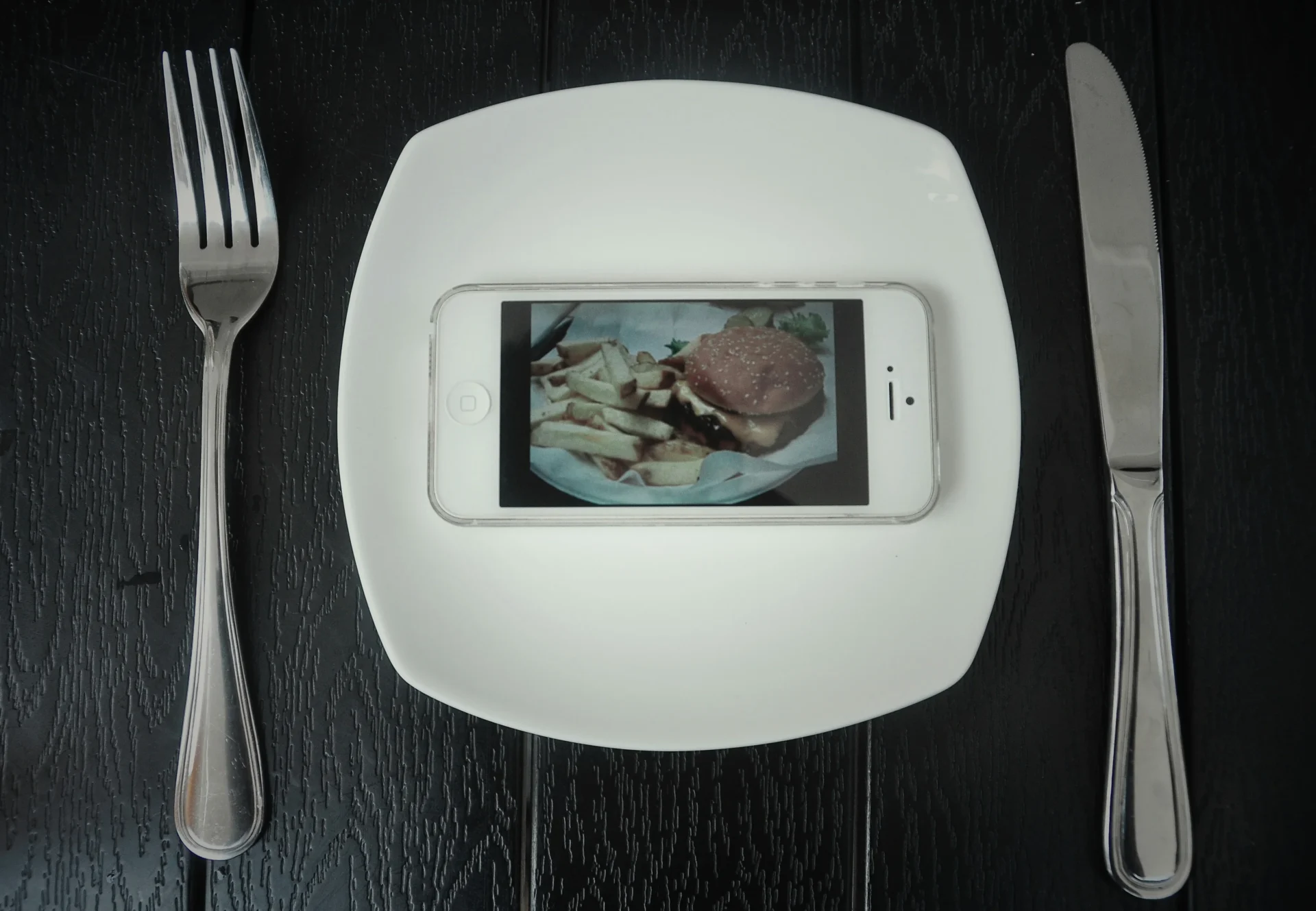 Smartphone displaying a burger and fries on a plate, illustrating the digital aspect of a modern food brand strategy.