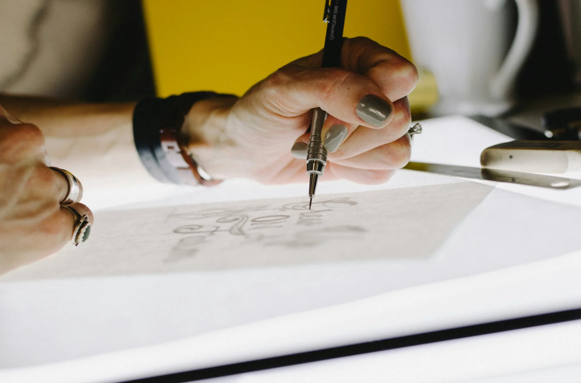 Close-up of a designer's hand sketching brand logos and visual elements for a brand identity project.