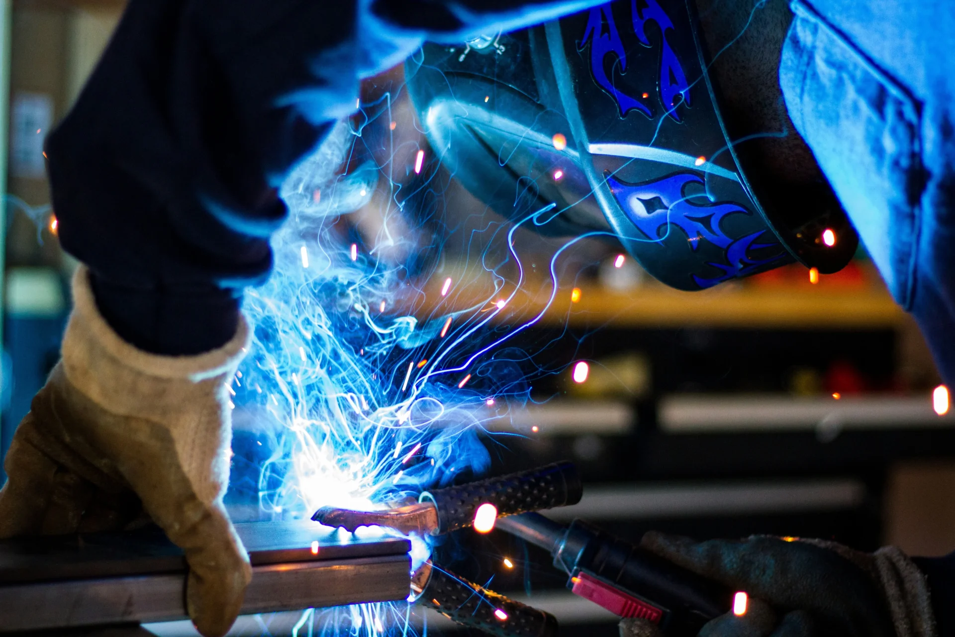 Welder performing welding operation, sparks visible, relevant to B2B industrial marketing.