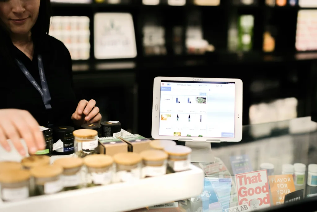 Tablet with product details on display at a retail counter, with jars and packaged goods, illustrating digital shopper marketing in a store setting.