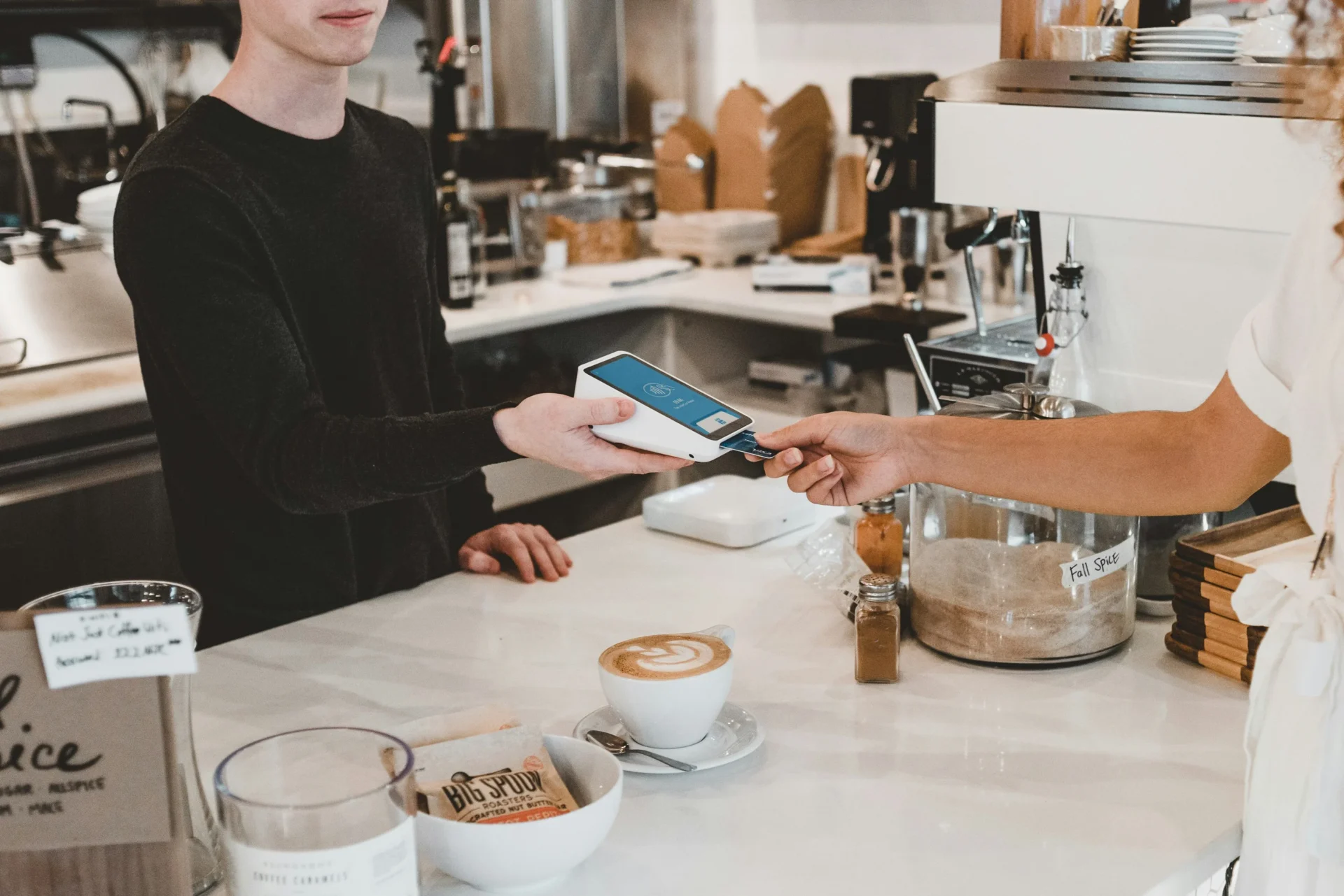 Customer paying with a card at a coffee shop, relevant to consumer behavior research on payment preferences.