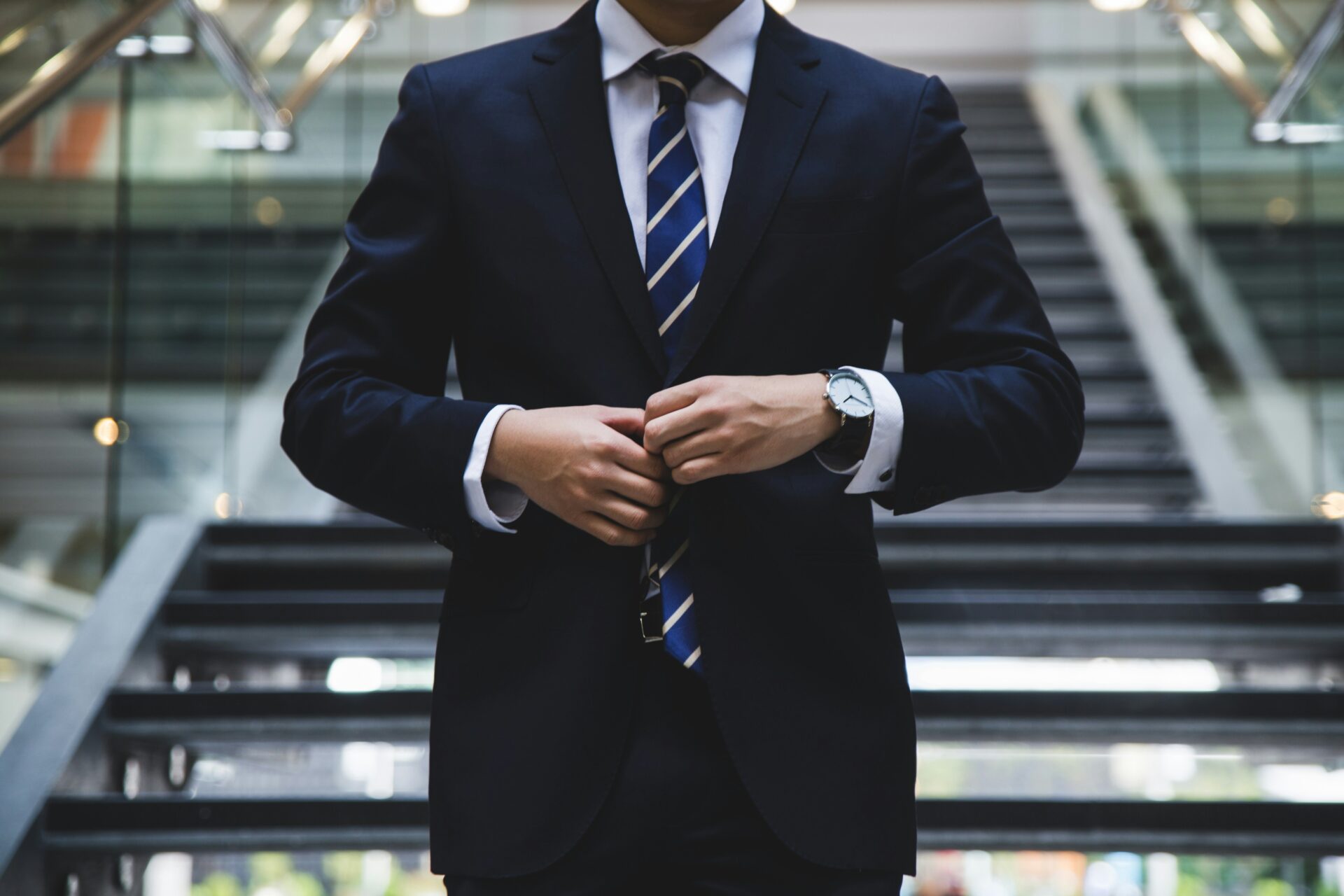 Lawyer in a suit adjusting his jacket in front of stairs.