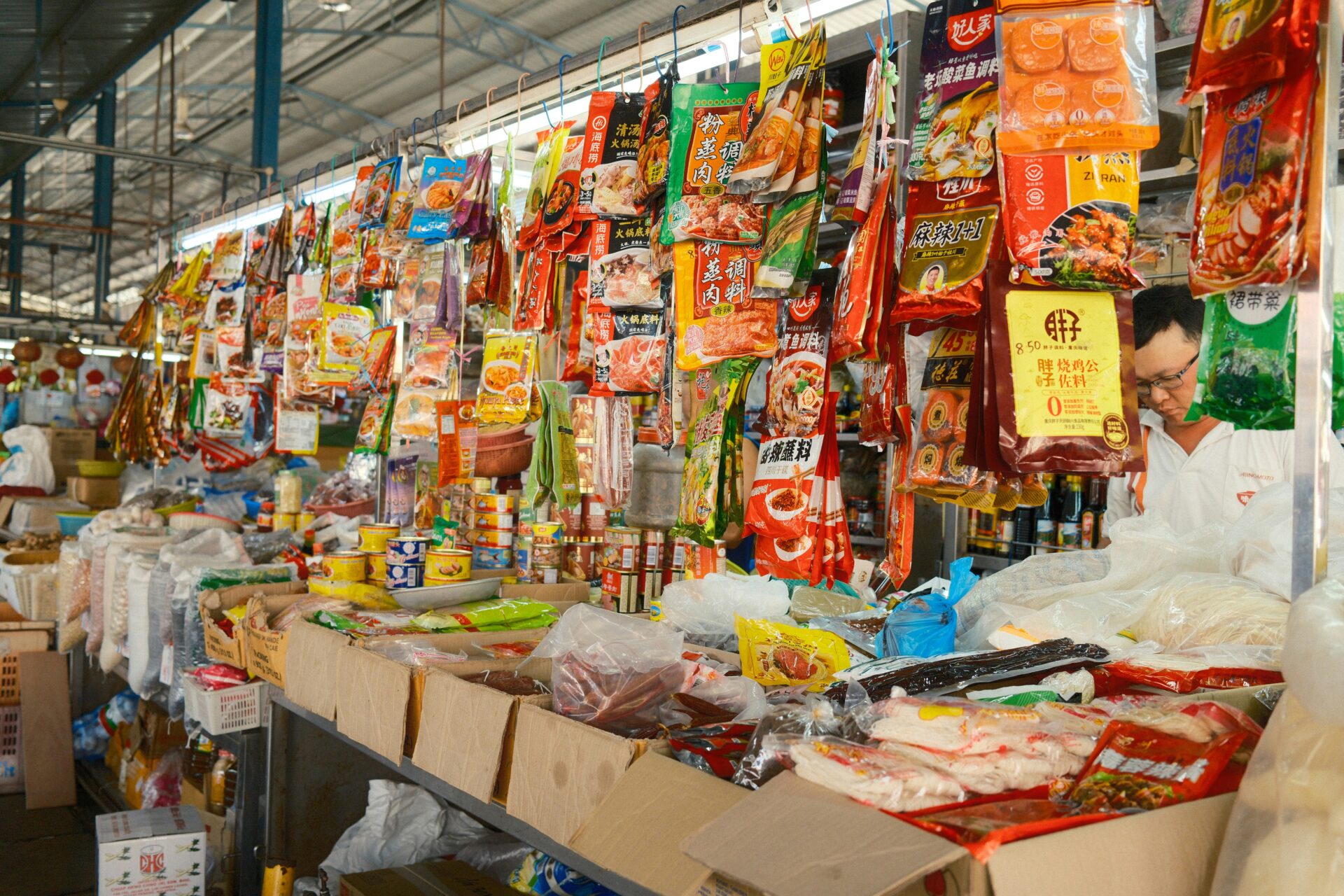Variety of packaged goods and canned foods displayed at a market stall.