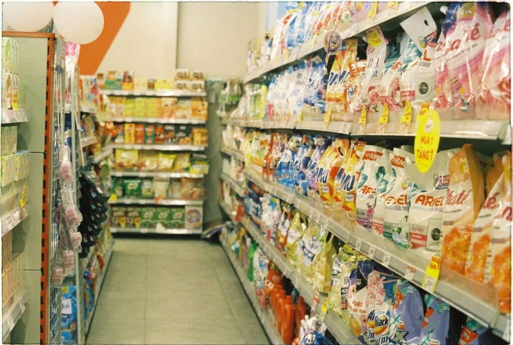 Aisles of a supermarket stocked with various consumer packaged goods on shelves.