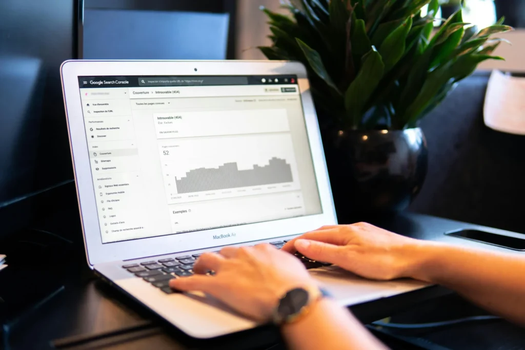 Hand using a mouse on an iMac displaying data, symbolizing the use of SEO tools for small business analytics.