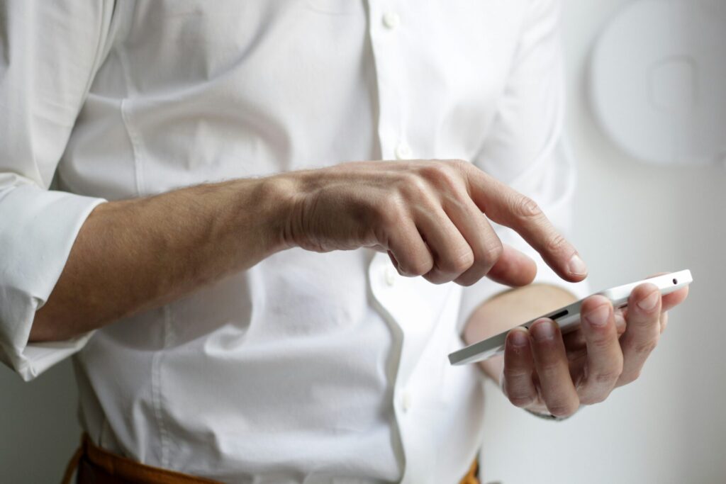 Hands using a smartphone, white shirt visible.
