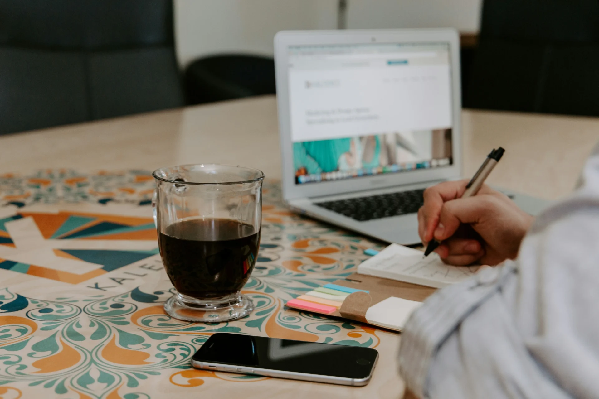 Person working from home with a laptop, coffee, and phone, ideal for illustrating an International SEO checklist.