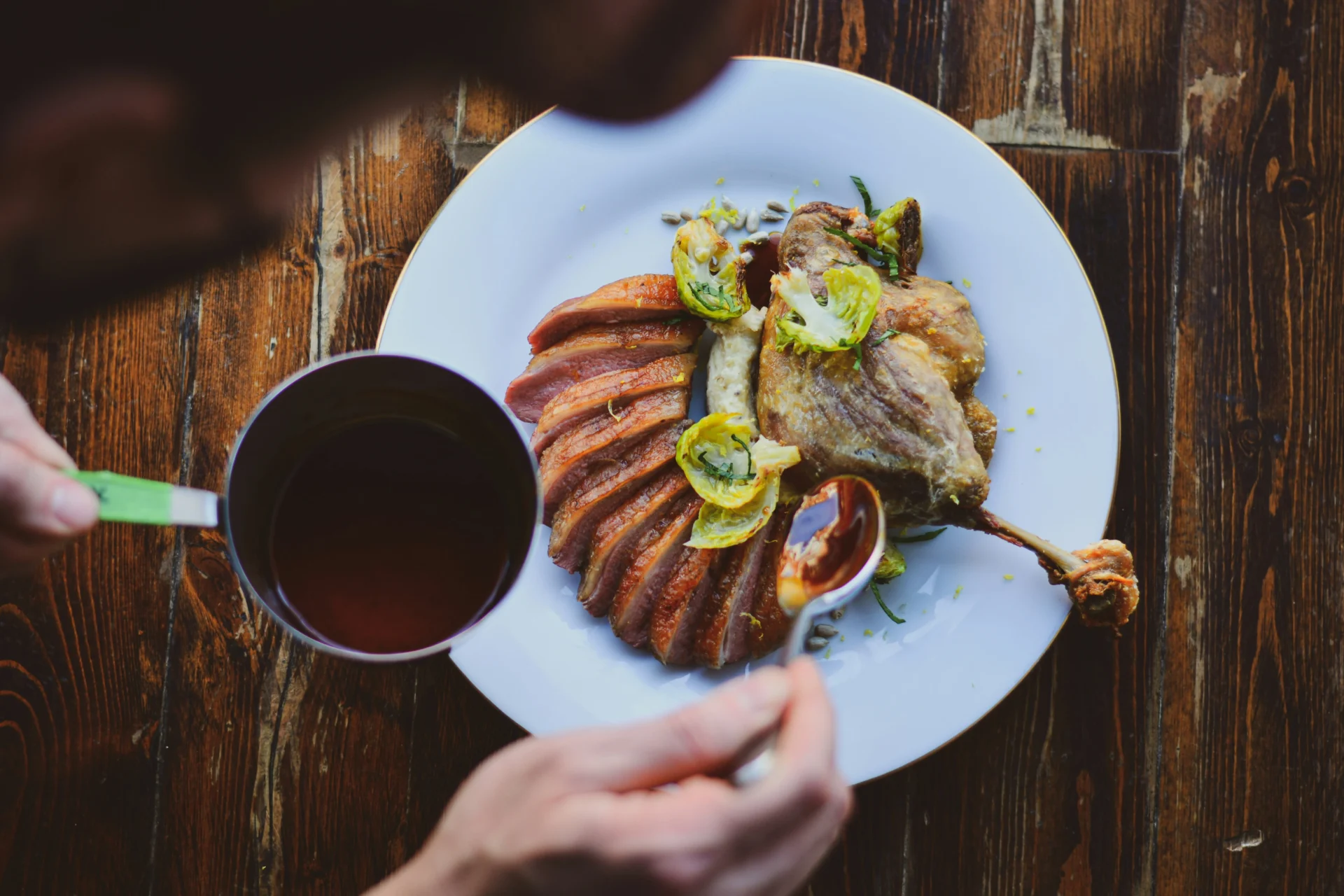 Confit duck leg and sliced duck breast with roasted Brussels sprouts, drizzled with sauce, perfect for a digital marketing strategy for restaurants.