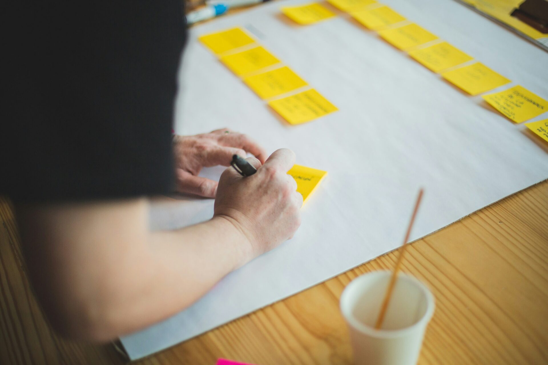 A person writing on a yellow sticky note during a content mapping session.