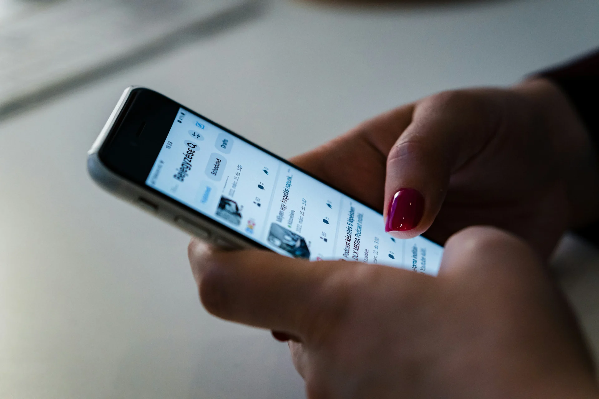 A person's hands holding a smartphone displaying a social media feed, perfect for inspiration for funny engagement posts for Facebook.