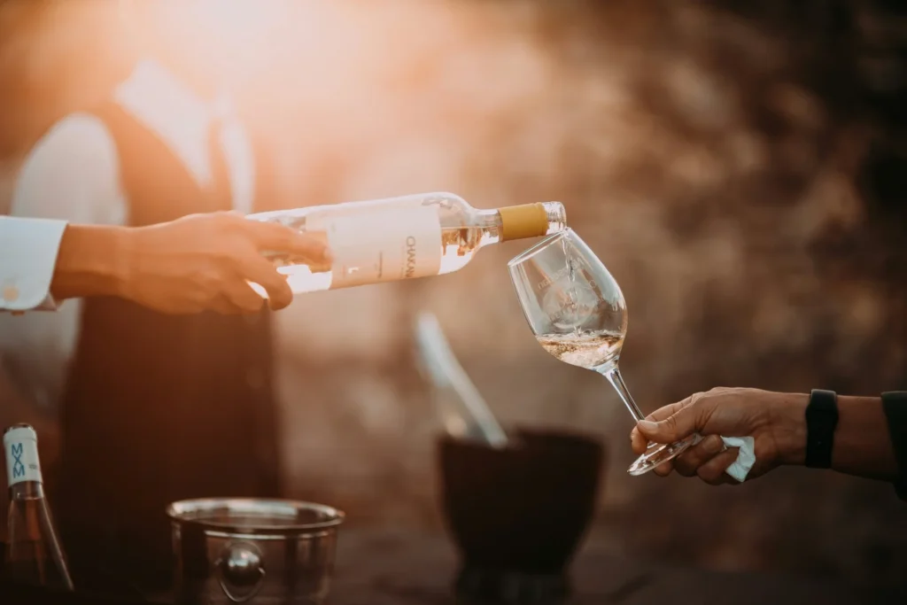 A person pouring white wine from a bottle into a glass, highlighting an aspect of a wine marketing strategy.
