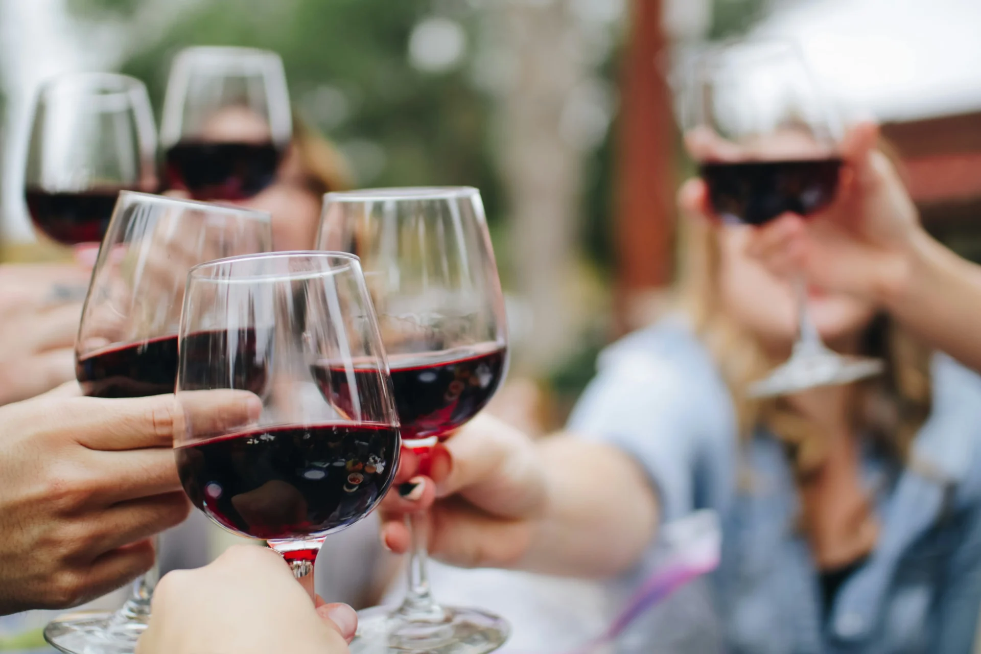 Multiple hands raising wine glasses in a toast, illustrating a successful wine marketing strategy.