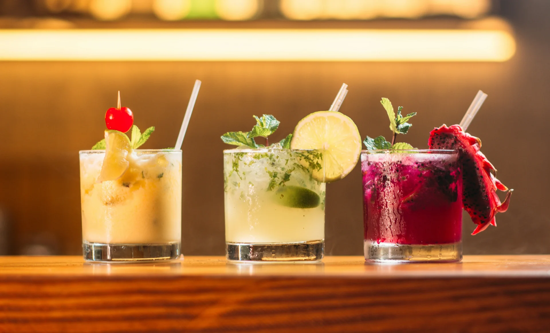 Three colorful cocktails on a bar counter, representing diverse products for a beverage marketing strategy.