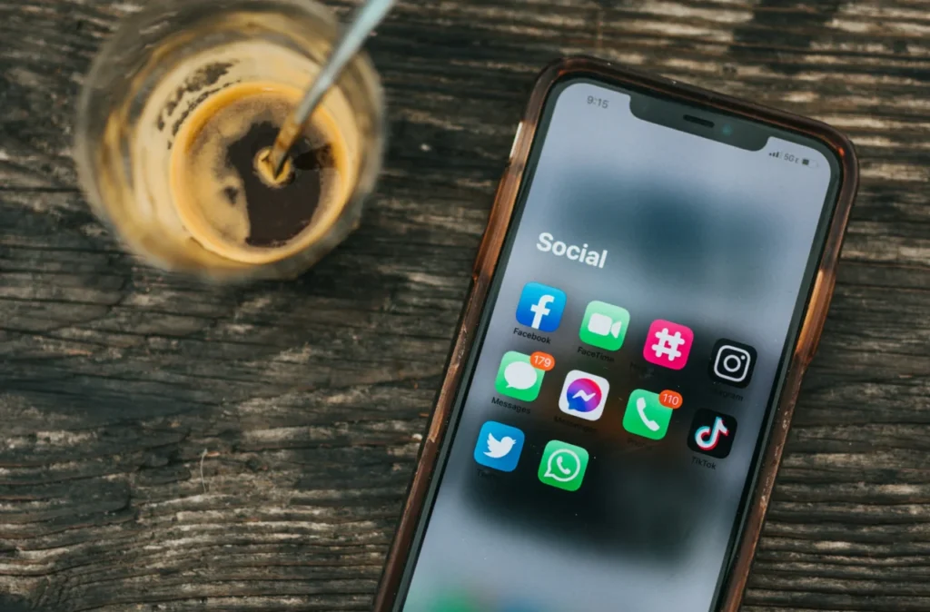 Smartphone on wooden table showing a "Social" folder with various social media apps, demonstrating how to increase social media engagement.