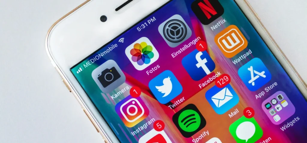 iPhone displaying various social media apps with a colorful background, representing engagement post ideas for social media.