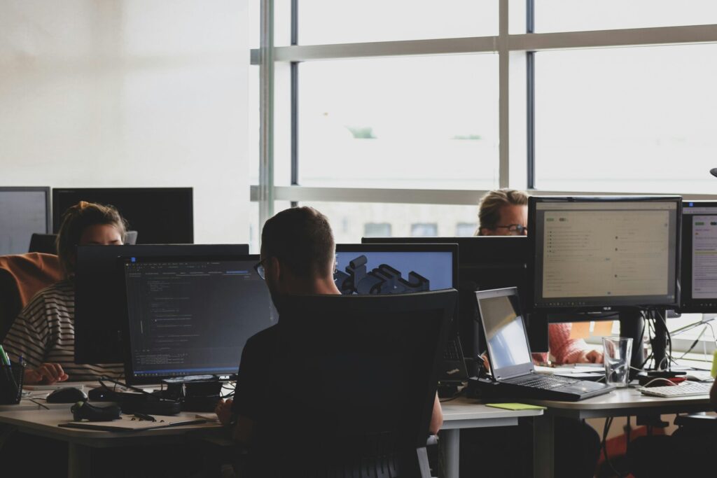 An office setting with multiple people working at computers, illustrating the application of local SEO versus traditional SEO in a business environment.