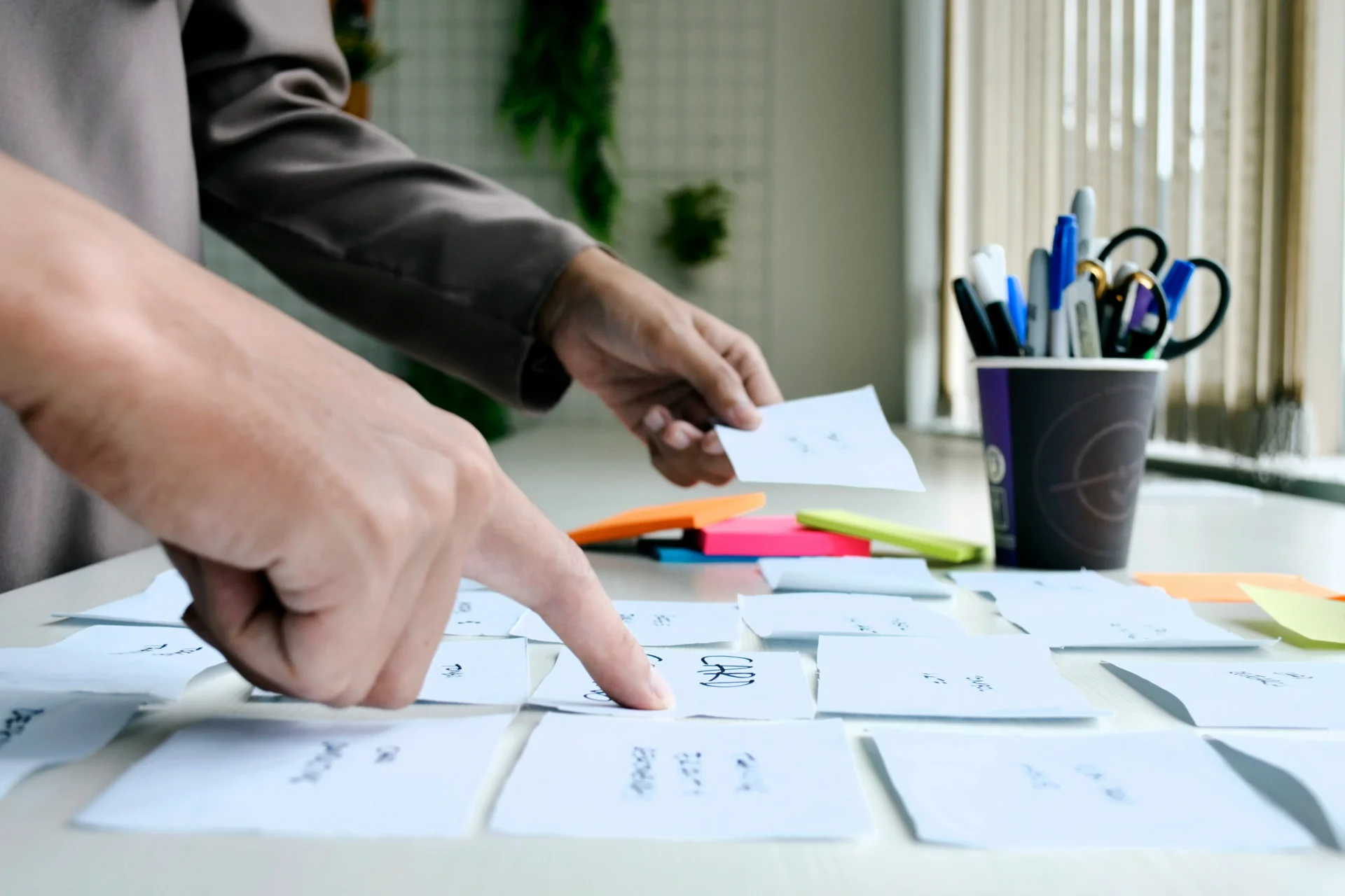 Hands organizing small cards on a table, symbolizing strategic planning for account-based marketing.