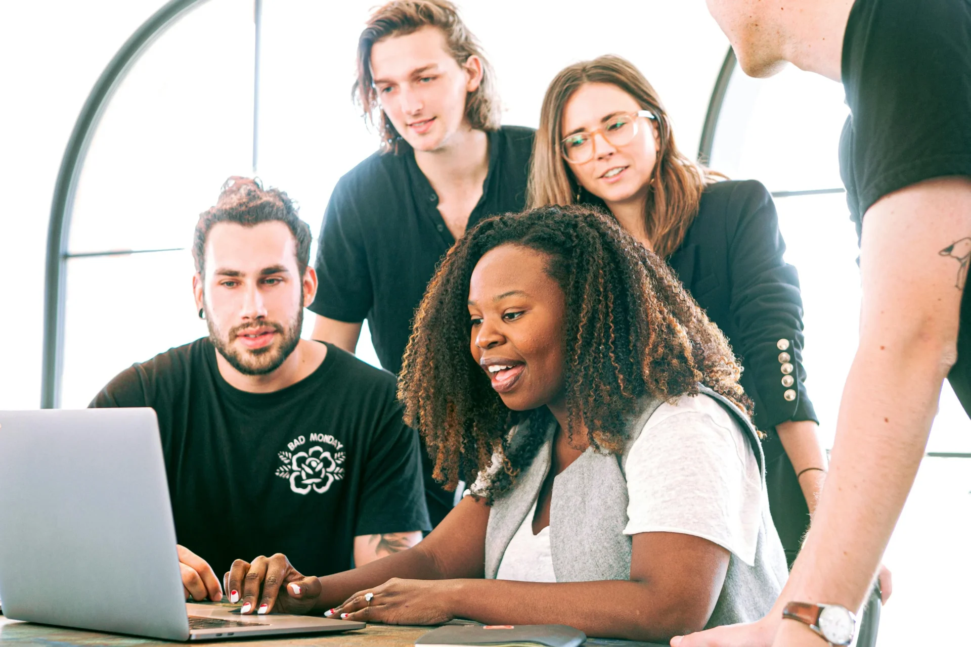 A diverse team of professionals collaboratively working on a laptop, discussing how to market their business effectively.