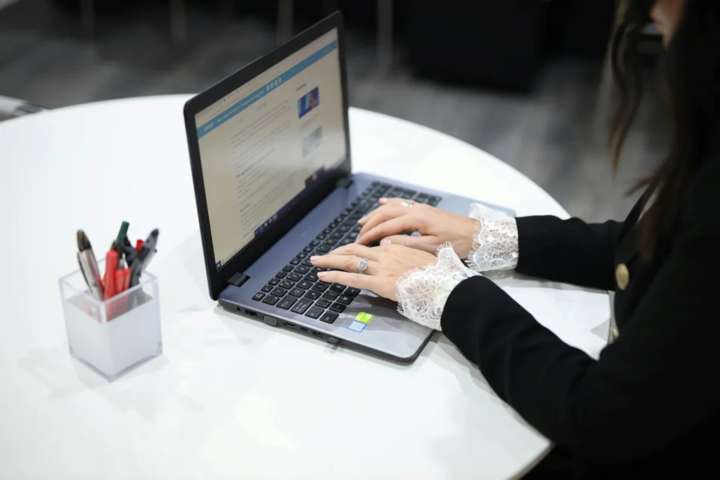 A professional woman types on a laptop, focusing on search engine optimization with considerations for local SEO vs national SEO.