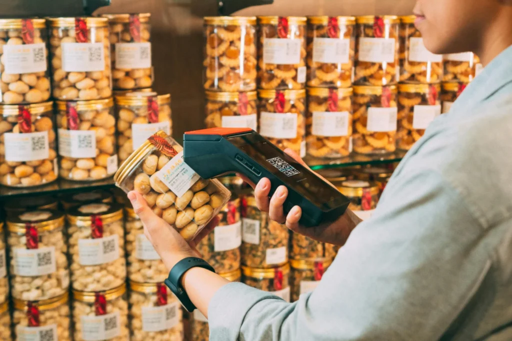 A store employee scans a jar of cookies with a barcode scanner, a key step in collecting data for consumer packaged goods analytics.