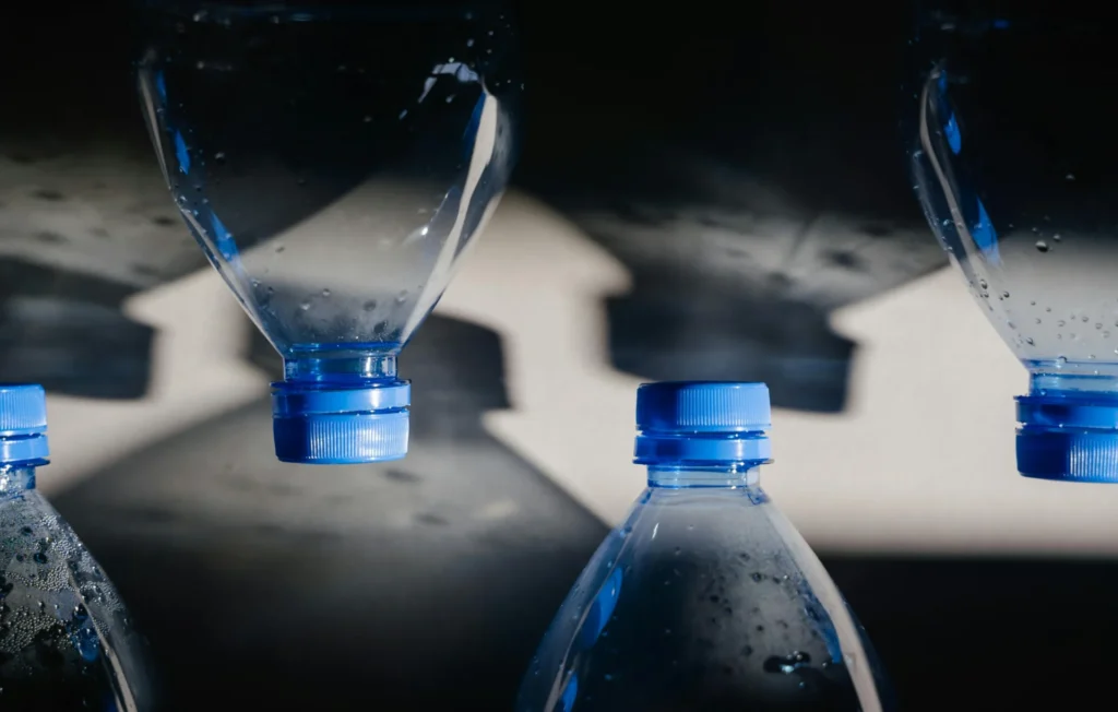 A row of empty and partially filled plastic water bottles, showcasing elements of bottled water branding like bottle shape and cap color.
