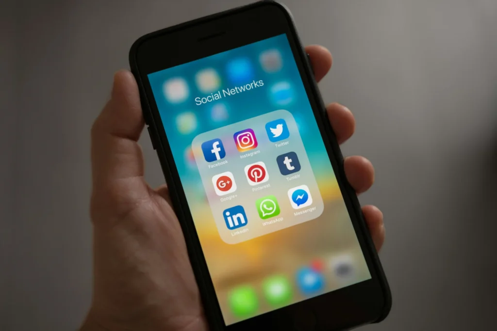 A smartphone displaying a folder of social network icons, including Facebook, Instagram, and LinkedIn, illustrating social media profile setup and integration.