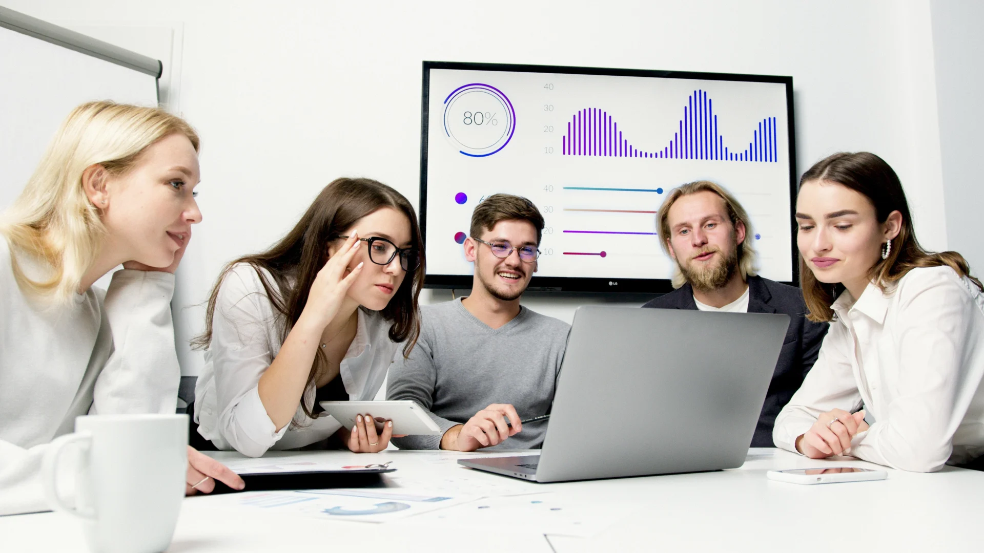 Marketing team reviewing data and charts on a large screen, discussing competitor keyword analysis results.