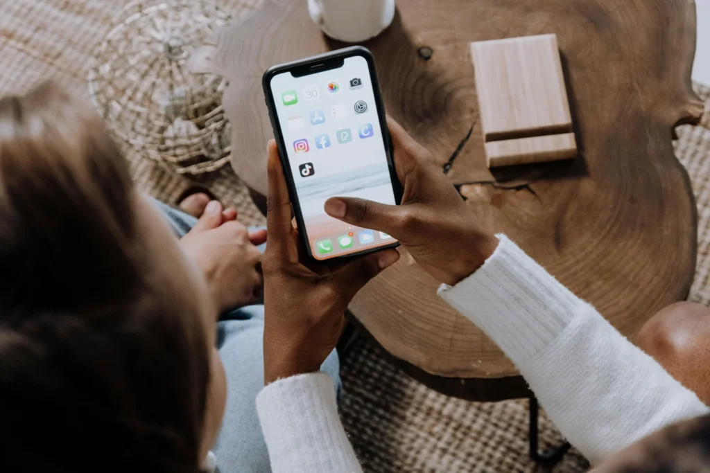 Close-up of a person holding a smartphone displaying social media app icons, including TikTok, with a focus on digital marketing and what is TikTok ads.
