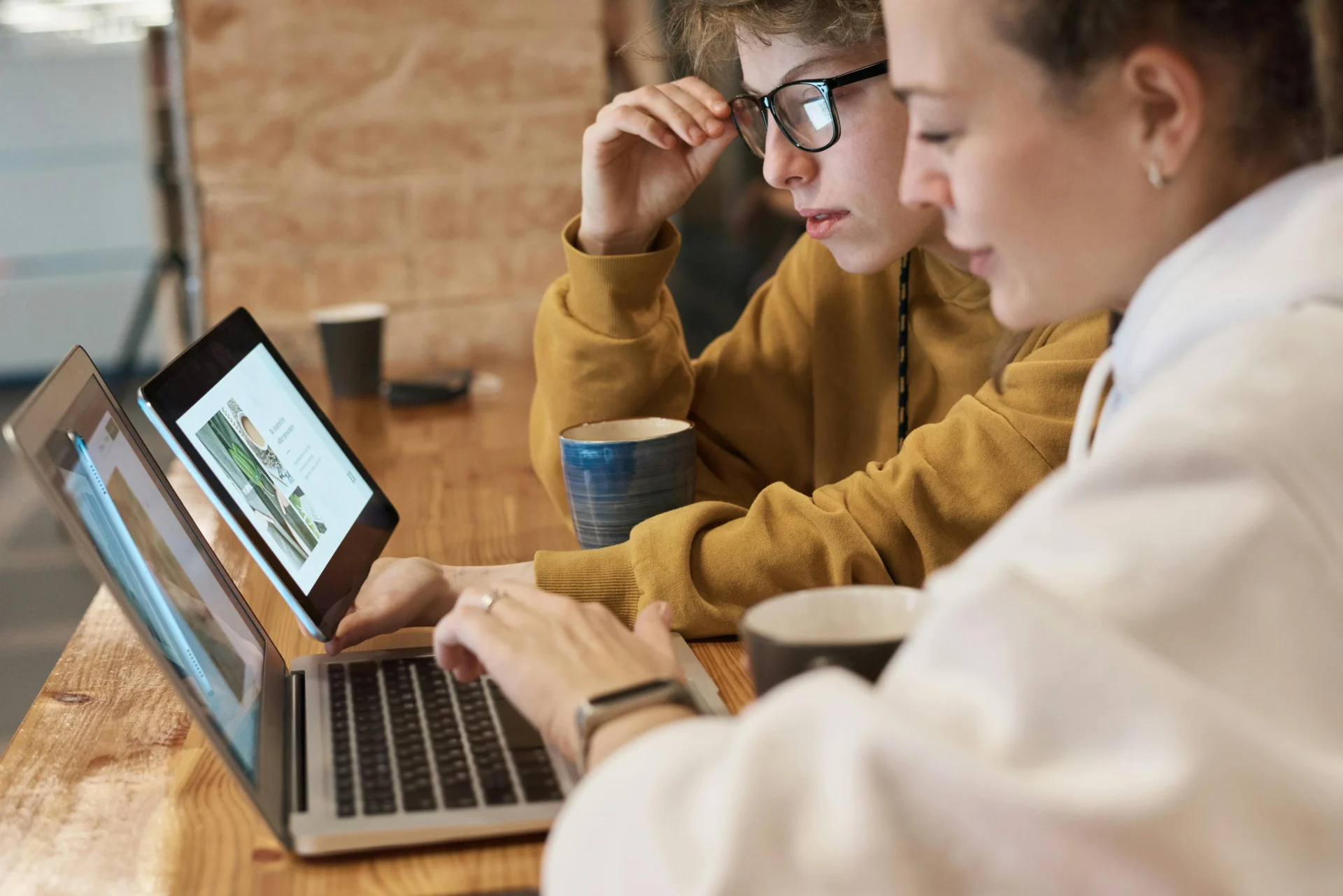 Close-up of two people collaborating on a laptop, researching the latest content marketing trends.