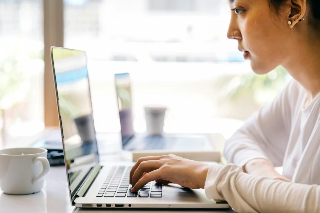 Woman typing on silver laptop focused on creating effective B2B display ads.