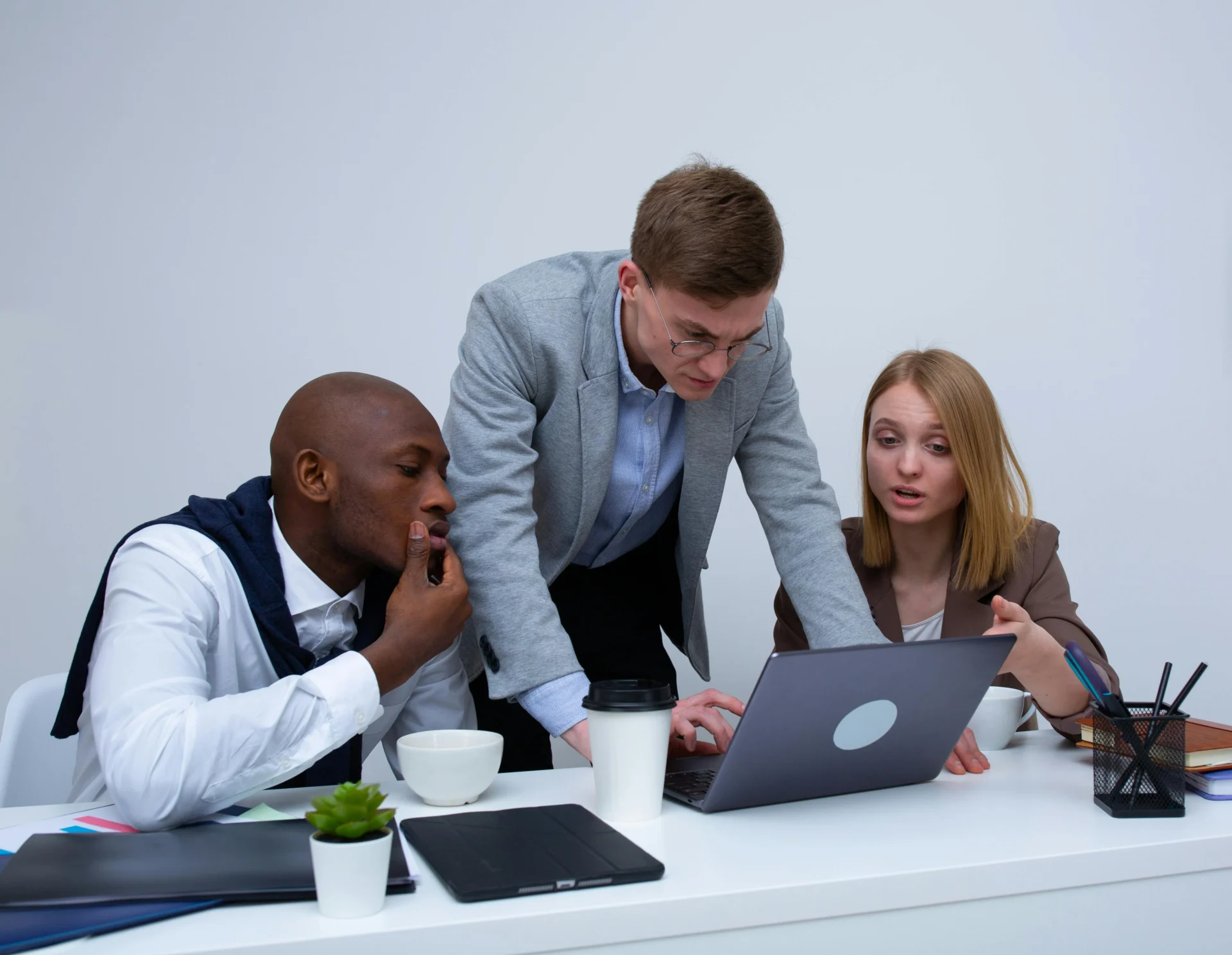Three diverse colleagues reviewing a laptop screen during a focused meeting on implementing a pillar content strategy.