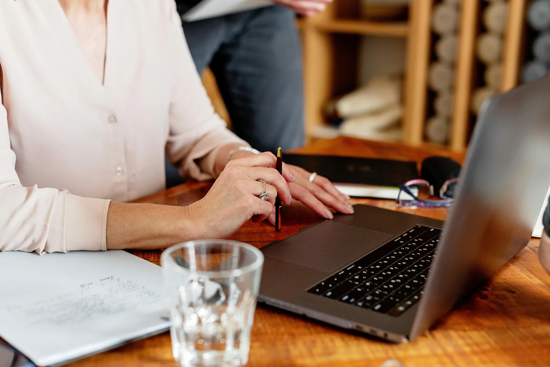 Professional reviewing notes and writing a content brief template on a laptop at a wooden desk.