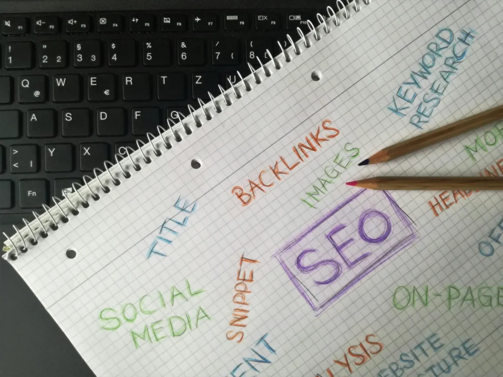 Notebook on laptop keyboard with hand-drawn SEO components and keywords: what is seo forecast