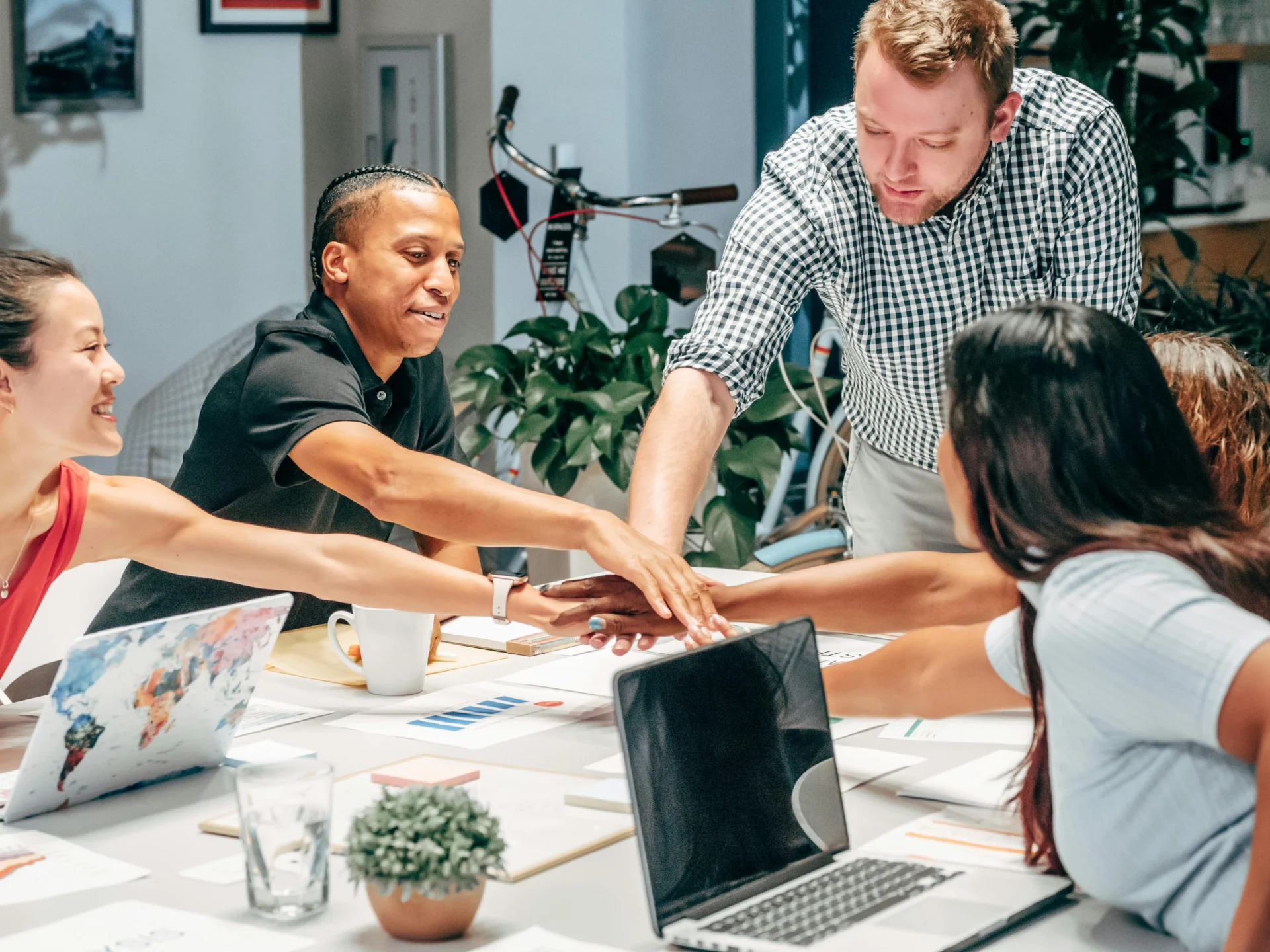 Diverse business team stacking hands over a table, signifying unity after deciding why hire a marketing agency.