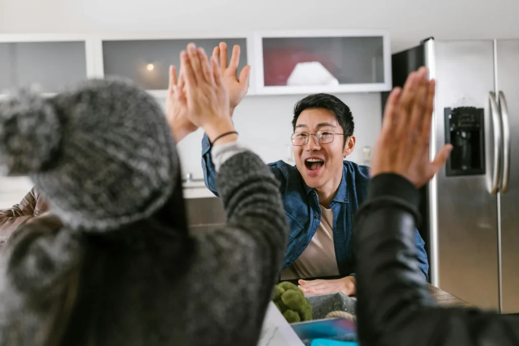 Startup team celebrating a successful brand launch with a high-five, showing the positive outcome of excellent branding services for startups and collaboration.